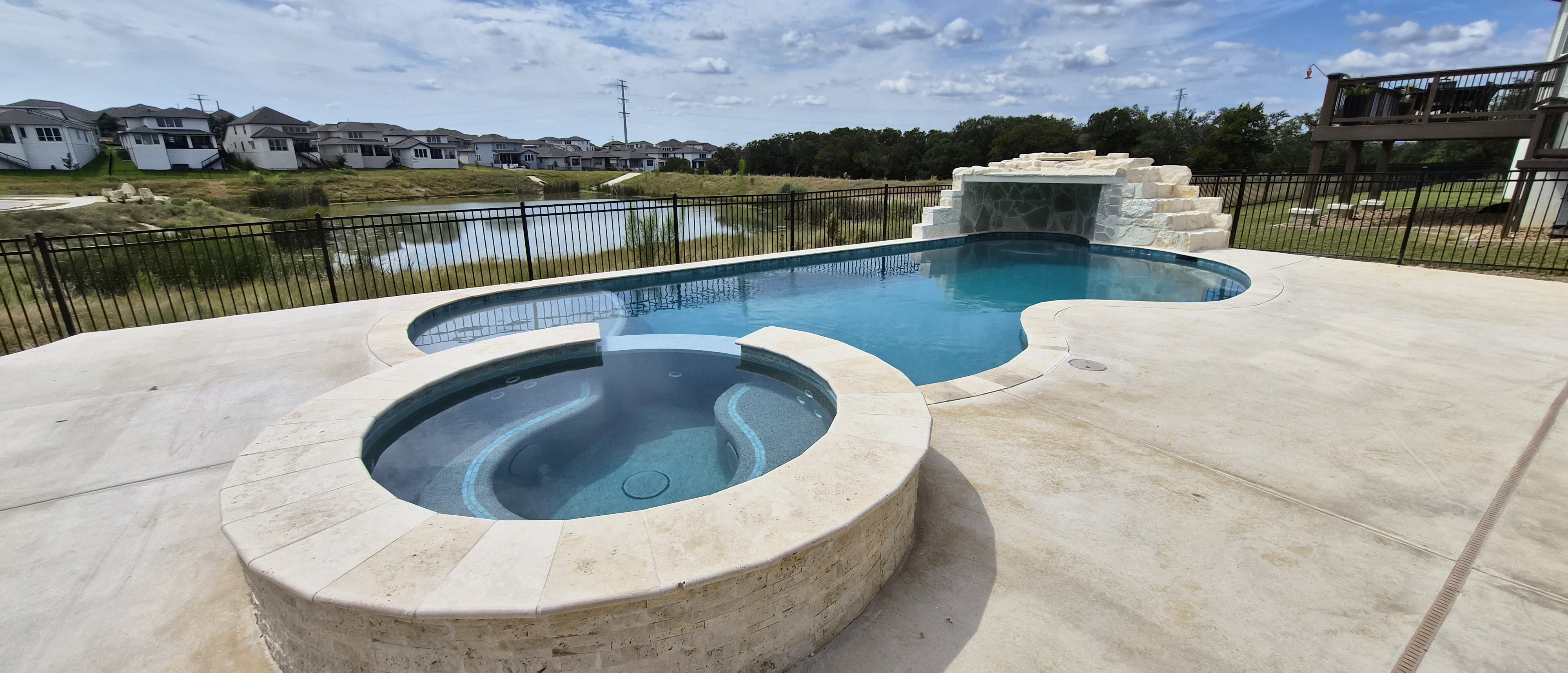 Luxury custom freeform pool with raised spa and stone waterfall wall built by J. Oliver Pools in New Braunfels, Texas