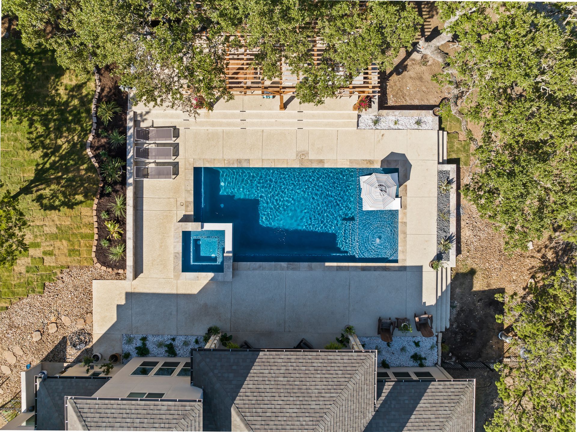 Aerial drone view of a completed custom gunite pool, spa, and travertine deck built by J. Oliver Pools