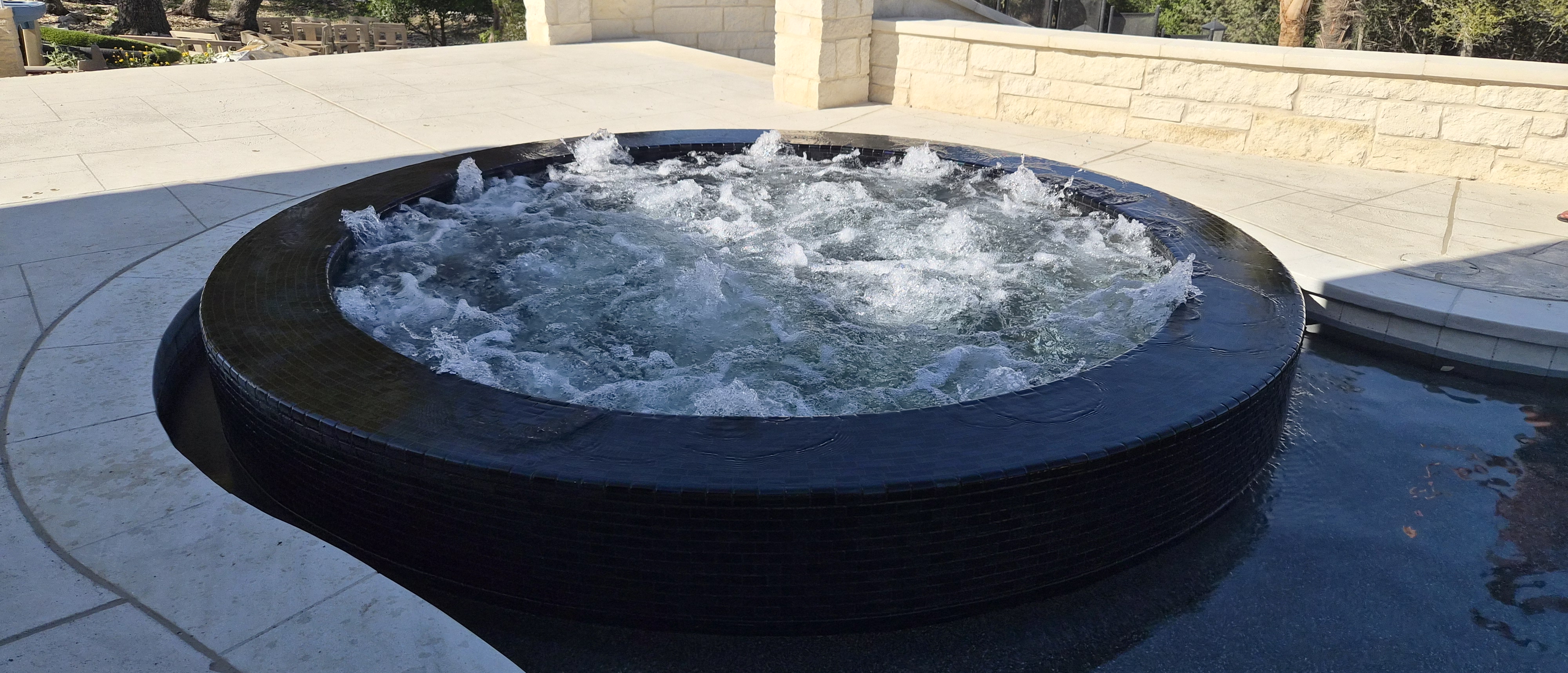 Bubbling raised spa with dark tile and jets built by J. Oliver Pools